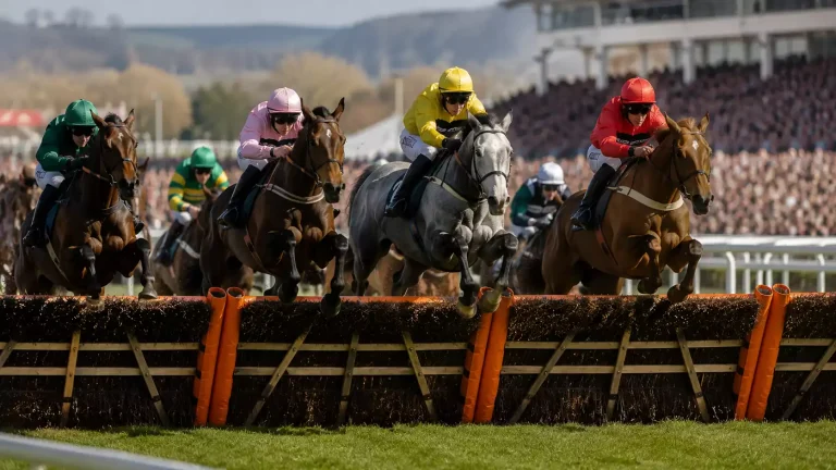 Grand National field jumping a fence at Aintree on the first circuit